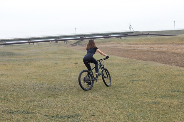 Garota em uma bicicleta de montanha em offroad belo retrato de um ciclista em tempo chuvoso garota fitness monta uma moderna bicicleta de montanha de fibra de carbono em roupas esportivas closeup retrato de uma garota de bandana vermelha