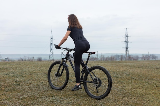 Garota em uma bicicleta de montanha em offroad belo retrato de um ciclista em tempo chuvoso Garota fitness monta uma moderna bicicleta de montanha de fibra de carbono em roupas esportivas Closeup retrato de uma garota de bandana vermelha