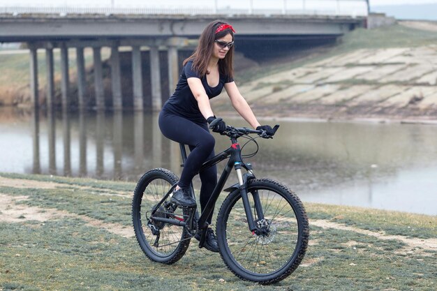 Garota em uma bicicleta de montanha no belo retrato offroad de um ciclista ao pôr do sol