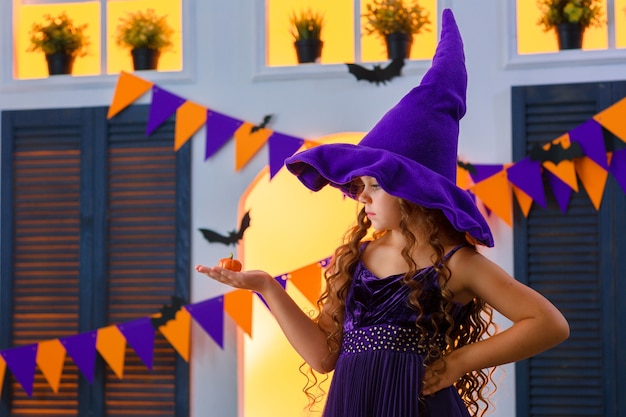 garota em uma fantasia de carnaval vai para a festa de Halloween com sua pequena abóbora.