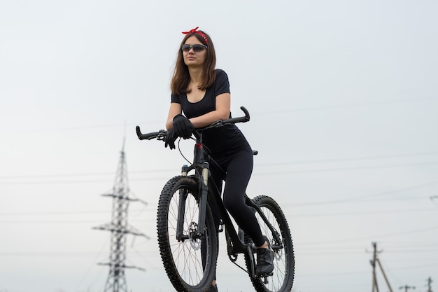 Garota em uma mountain bike no offroad lindo retrato de um ciclista em tempo chuvoso