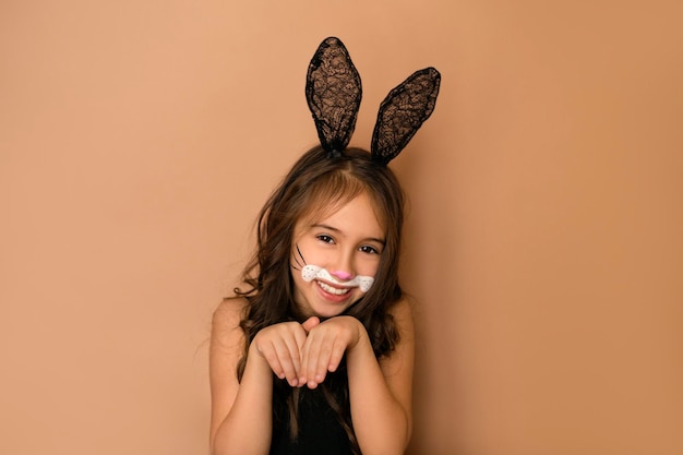 Garota engraçada com cabelos cacheados e orelhas de renda retrata coelho com patas dobradas