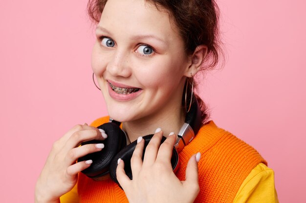 Garota engraçada em um estilo de vida de entretenimento musical de fones de ouvido de jaqueta laranja inalterado