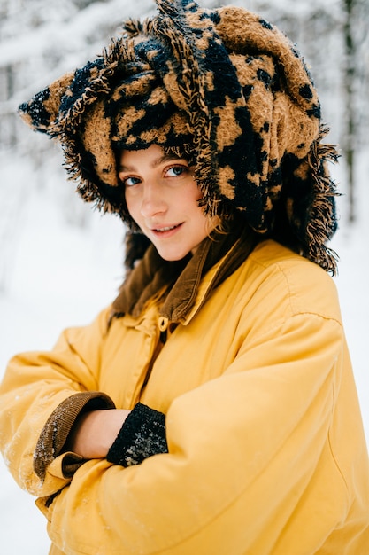 Garota engraçada jovem hippie com jaqueta amarela e turbante do lenço posando na floresta de neve