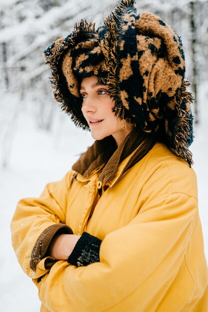 Garota engraçada jovem hippie com jaqueta amarela e turbante do lenço posando na floresta de neve