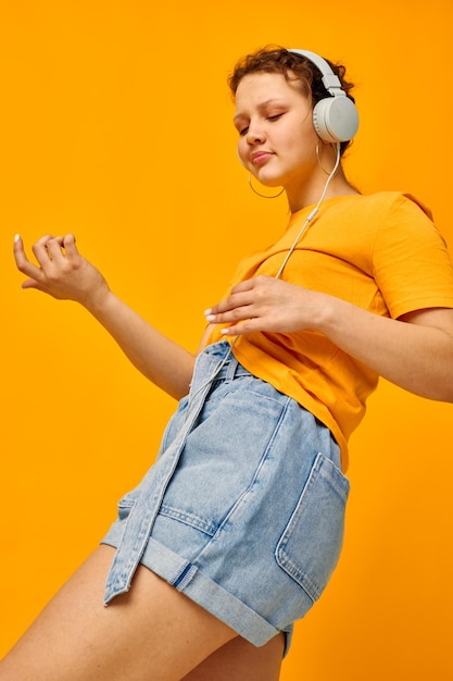 Garota engraçada ouvindo música em fones de ouvido estilo jovem fundo amarelo inalterado