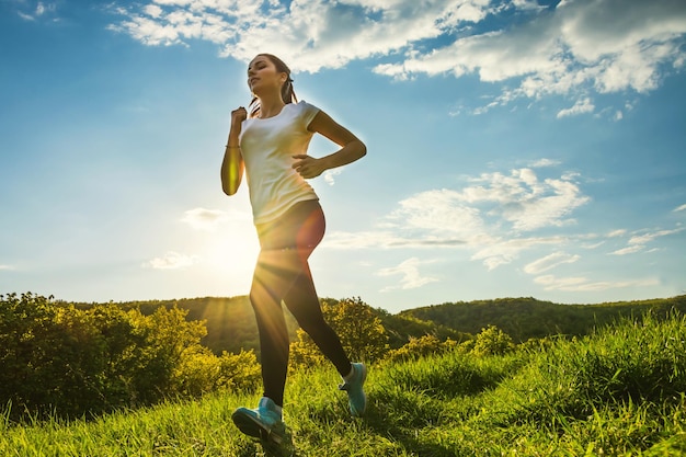 Garota esportiva corre crosscountry ao pôr do sol na primavera