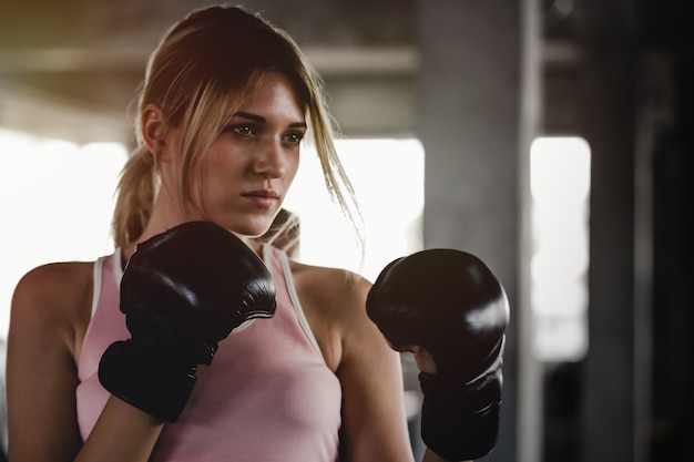 Garota esportiva de retrato mulher bonita com as luvas de boxe de volta treinando na Academia