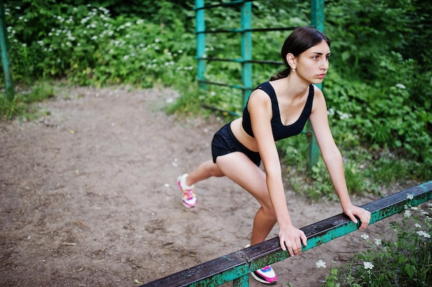 Garota esportiva em roupas esportivas se exercitando em exercícios de barra horizontal em um parque verde e treinando na natureza Um estilo de vida saudável