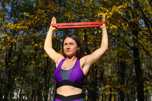 Garota esportiva fazendo exercícios com um elástico de fitness no parque