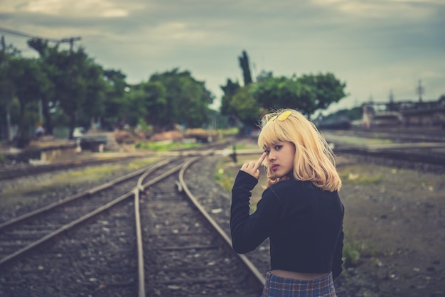 Garota esportiva mostra o dedo médio foda-se na sua cabeça na ferrovia Conceito de retrato de estilo de vida engraçado ao ar livre de brutal rebelde punk furioso indecente linda garota tailandesa mulher tailandesa garota dourada hairshipster