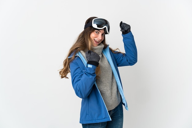 Garota esquiadora com óculos de snowboard isolados no fundo branco comemorando uma vitória