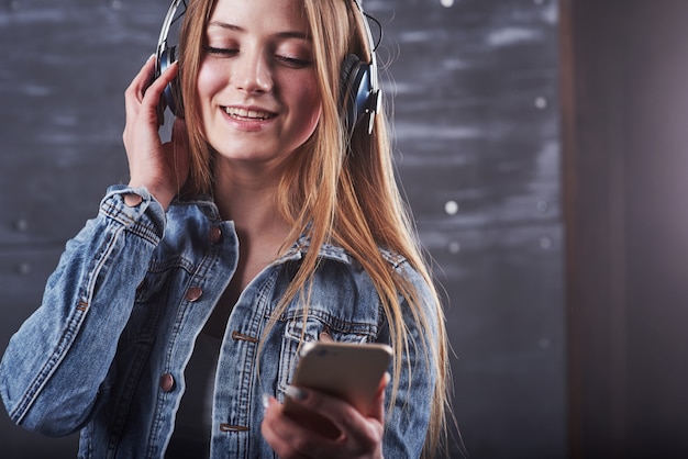 Garota está posando no estúdio ouve música em fones de ouvido