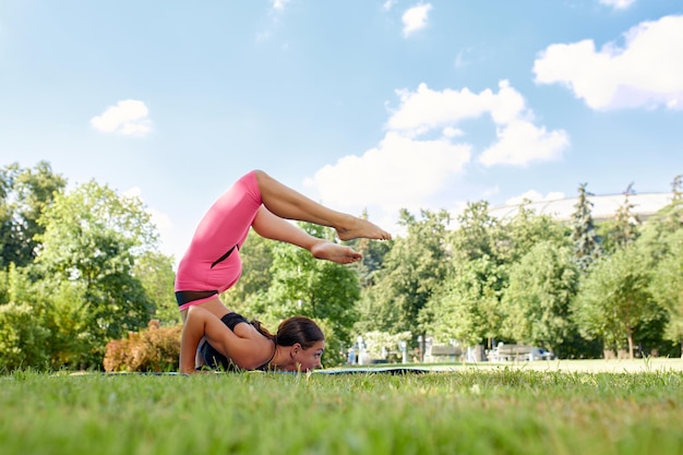 Garota europeia em um agasalho leve fazendo ioga no parque à tarde no verão Ginástica na natureza Mulher fina ao ar livre