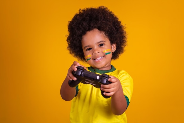 Garota fã de futebol brasileiro vestindo uniforme amarelo e segurando um controlador de videogame em fundo amarelo