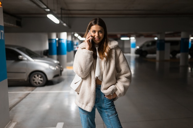 Garota falando ao telefone em um estacionamento subterrâneo