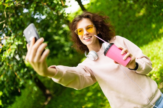 garota faz selfie em uma parede do parque verde