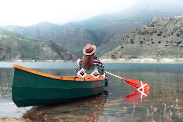 garota fazendo canoagem em um lago nas montanhas em um dia nublado. Atmosfera sombria no lago bylym