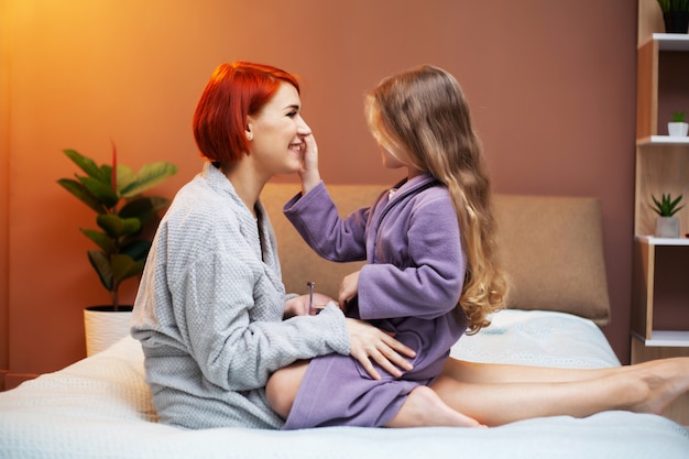 Garota fazendo maquiagem mãe, em casa na cama