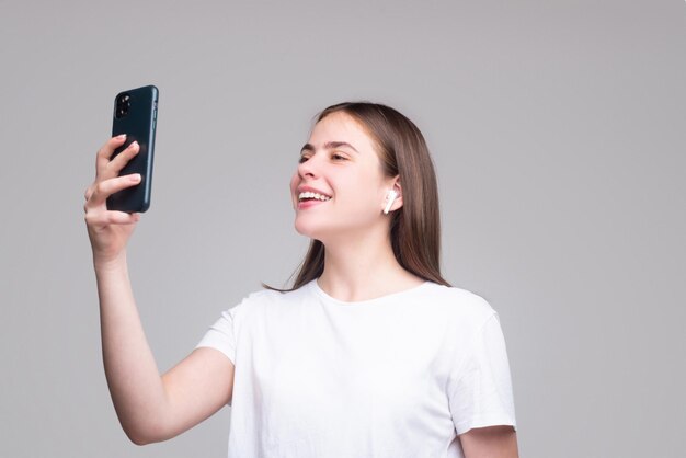 Garota fazendo selfie jovem sobre fundo cinza isolado com telefone