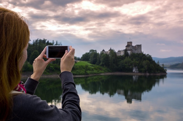 Garota fazendo uma sessão de fotos do castelo niedzica com o smartphone, Polônia