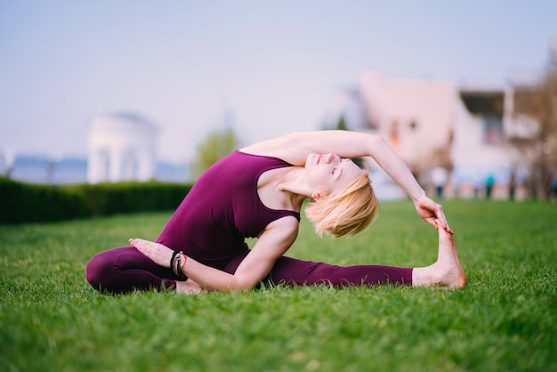 Garota fazendo yoga na grama verde em um dia ensolarado