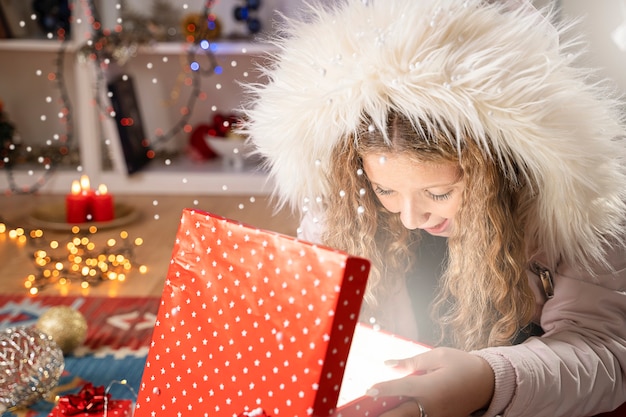 Garota feliz abrindo uma caixa de presente de natal em clima de natal