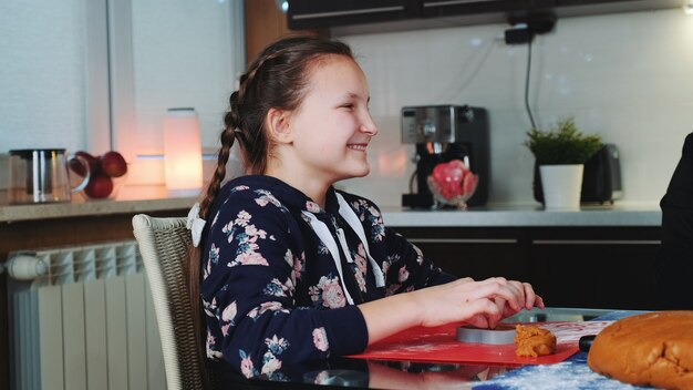 Garota feliz, ajudando a mãe a fazer biscoitos saborosos