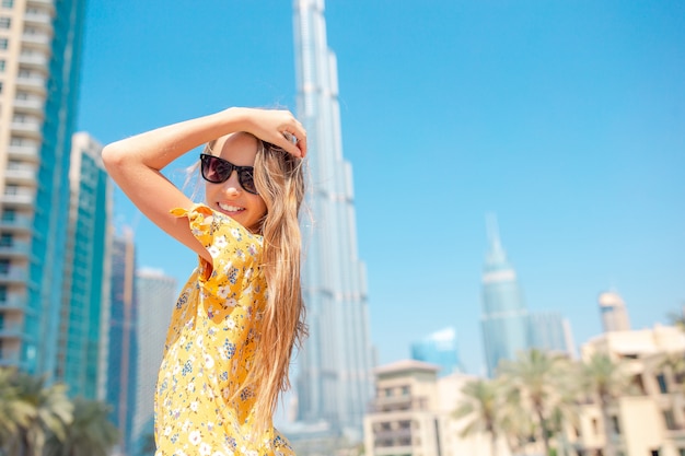 Garota feliz andando em dubai com arranha-céus burj khalifa em segundo plano.