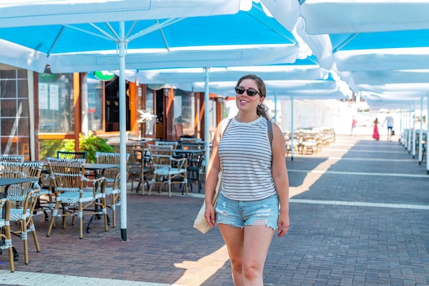Garota feliz andando no restaurante e área de marina no verão