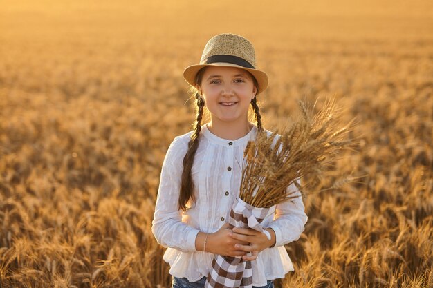 Garota feliz andando no trigo dourado, curtindo a vida no campo.