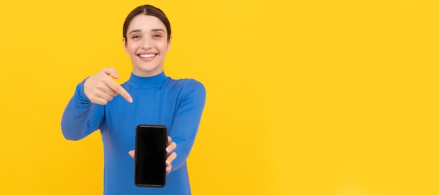 Garota feliz apontando o dedo na apresentação do espaço de cópia da tela do smartphone Banner de retrato de rosto isolado de mulher com espaço de cópia