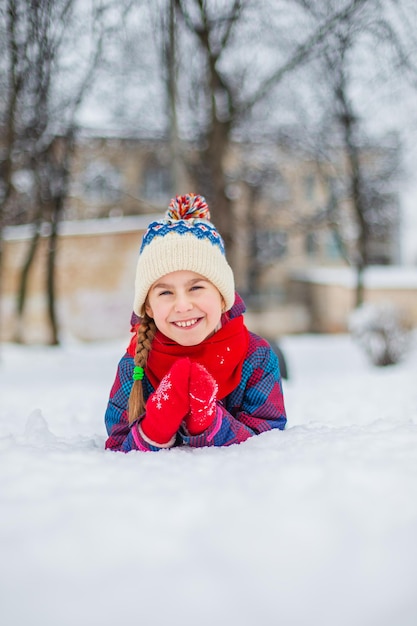 Garota feliz brincando com neve em uma caminhada de inverno nevado fazendo bolas de neve no parque