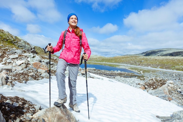 Garota feliz caminhadas com bastões de trekking nas montanhas. Noruega