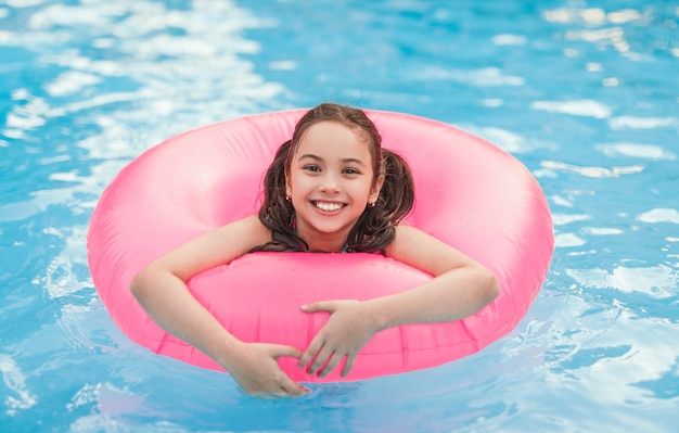 Garota feliz com anel inflável, aproveitando a piscina do resort