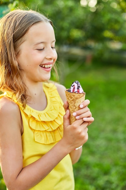 Garota feliz com aparelho comendo casquinha de sorvete italiano sorrindo enquanto descansava no parque no dia de verão