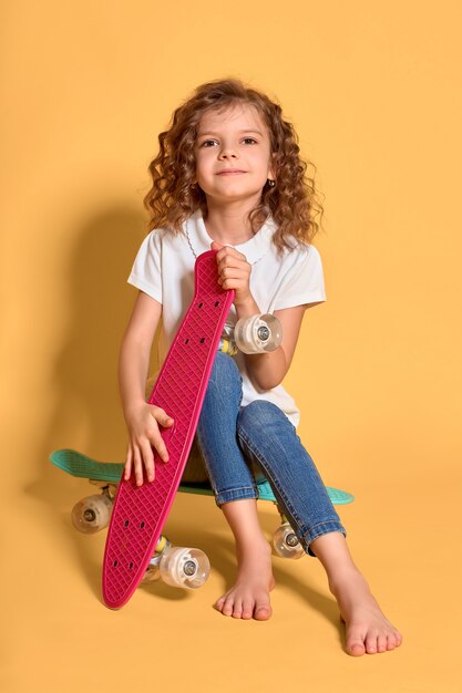 Garota feliz com cabelos cacheados e fones de ouvido se divertindo com placas de centavo