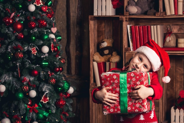 Garota feliz com carinho tem um presente de Natal nas mãos