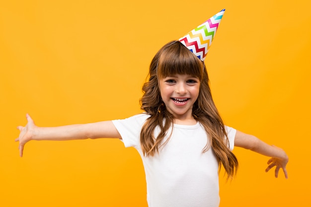 Garota feliz com chapéu de festa em amarelo