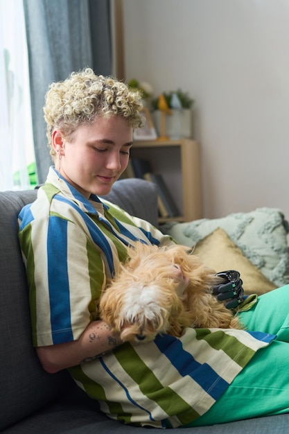 Garota feliz com deficiência física brincando com cachorro de raça pura no sofá