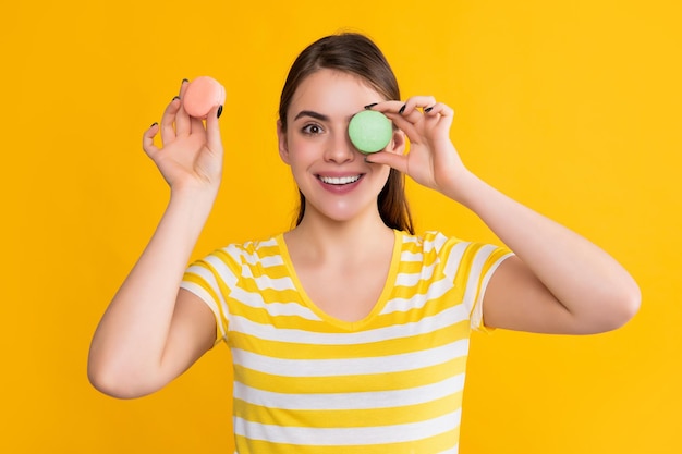 Garota feliz com macaron em fundo amarelo