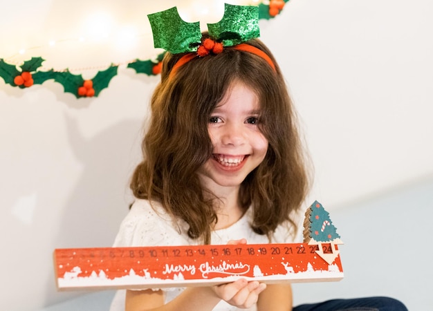 Garota feliz com régua de calendário do advento em suas mãos