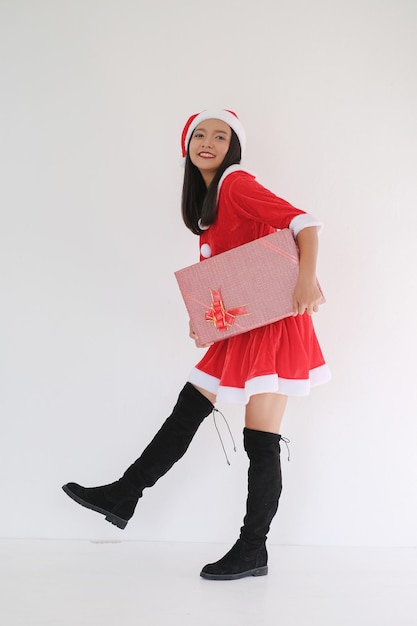Garota feliz com vestido de Papai Noel com caixa de presente em fundo branco na festa de Natal