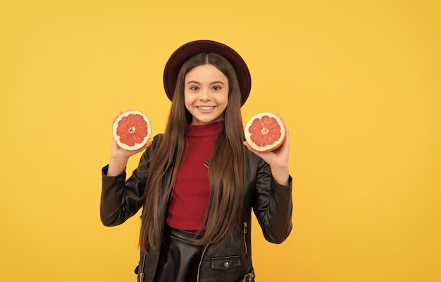 Garota feliz de infância saudável de alimentos frescos orgânicos naturais em couro segura toranja