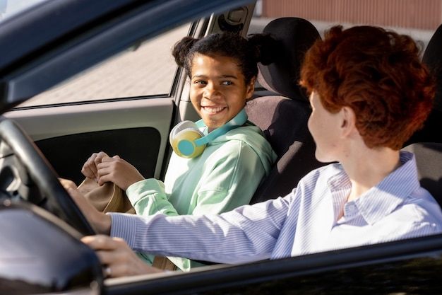 Foto garota feliz de raça mista olhando para uma jovem no carro