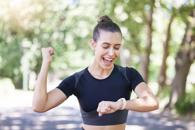 Garota feliz de sucesso ou corredor com smartwatch no parque para frequência cardíaca para monitorar o progresso do treinamento ou exercício Animado sim ou atleta de esportes saudável com cronômetro comemora treino de corrida ou fitness