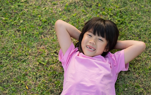 Garota feliz, deitada na grama, play ground