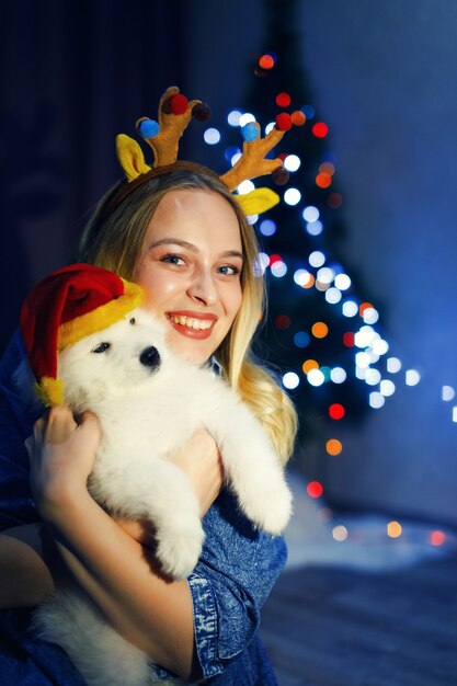 Garota feliz em chifre com cachorro husky samoiedo em decorações de Natal
