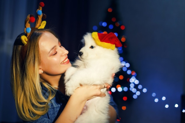Foto garota feliz em chifre com cachorro husky samoiedo em decorações de natal