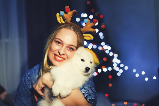 Garota feliz em chifre com cachorro husky samoiedo em decorações de Natal